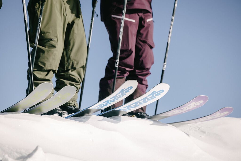 Two skiers on K2 skis preparing to drop in to a run