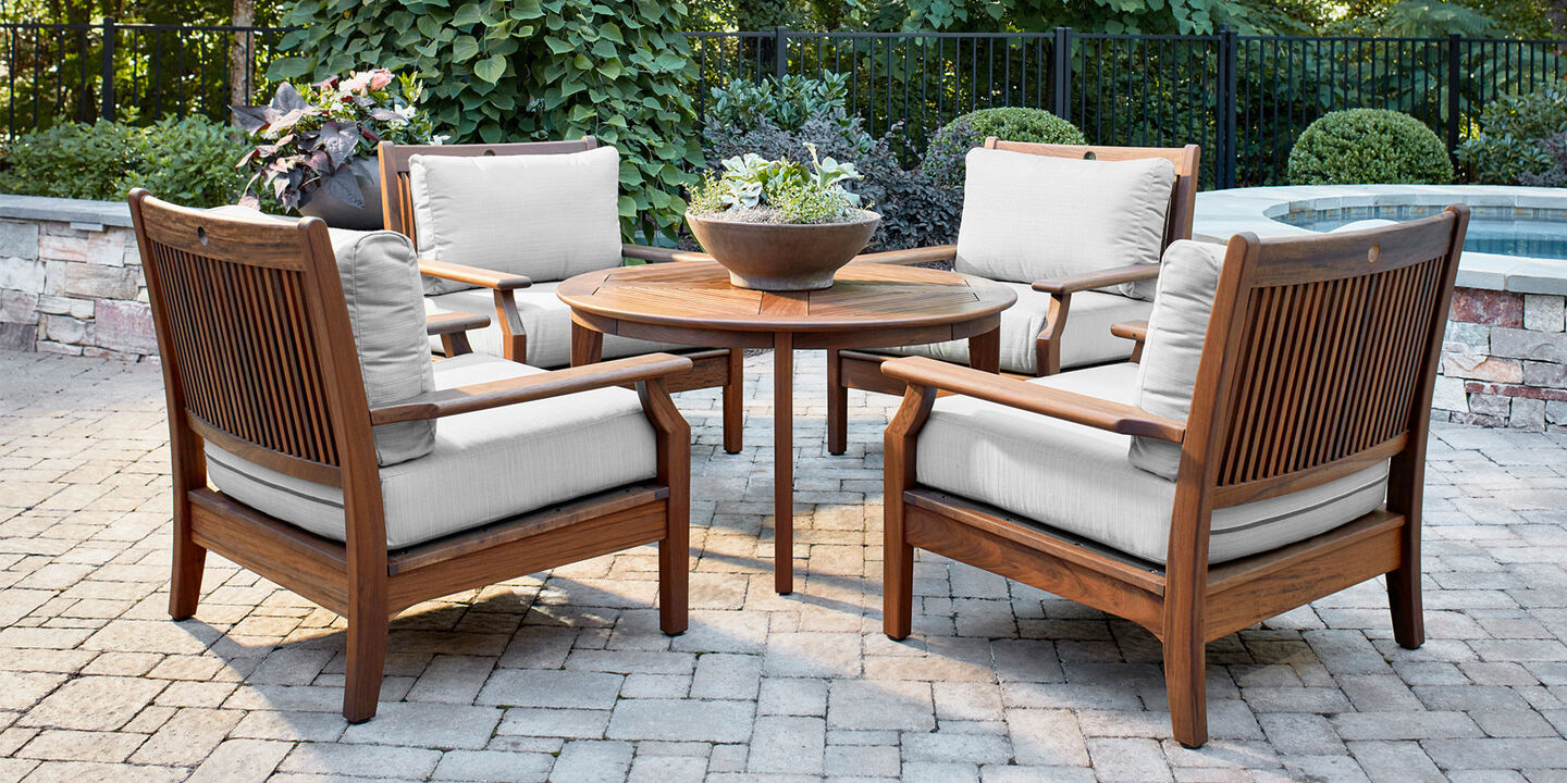 Four ipe wood outdoor lounge chairs with cushions with chat table on stone patio