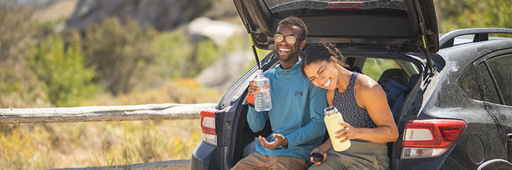 couple sitting in back of car hydrating couple sitting in back of car hydrating