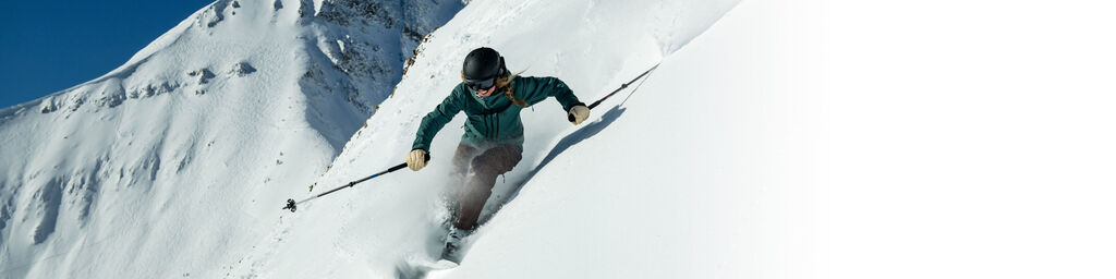 Downhill skier on steep terrain in deep powder