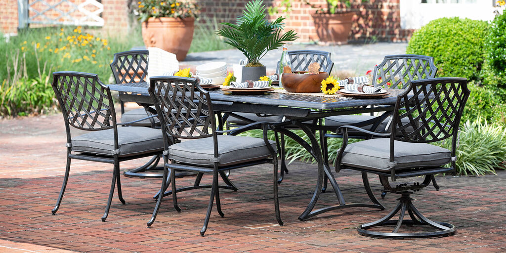 Aluminum outdoor dining chairs and swivel rockers with cushions and long rectangular table on a patio