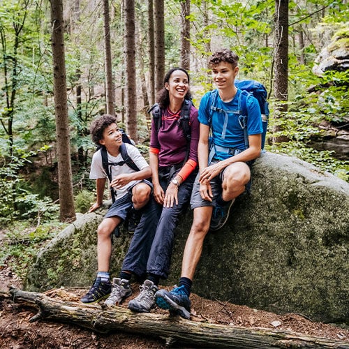 hikers outside just off the trail leaning on a rock and taking a break 