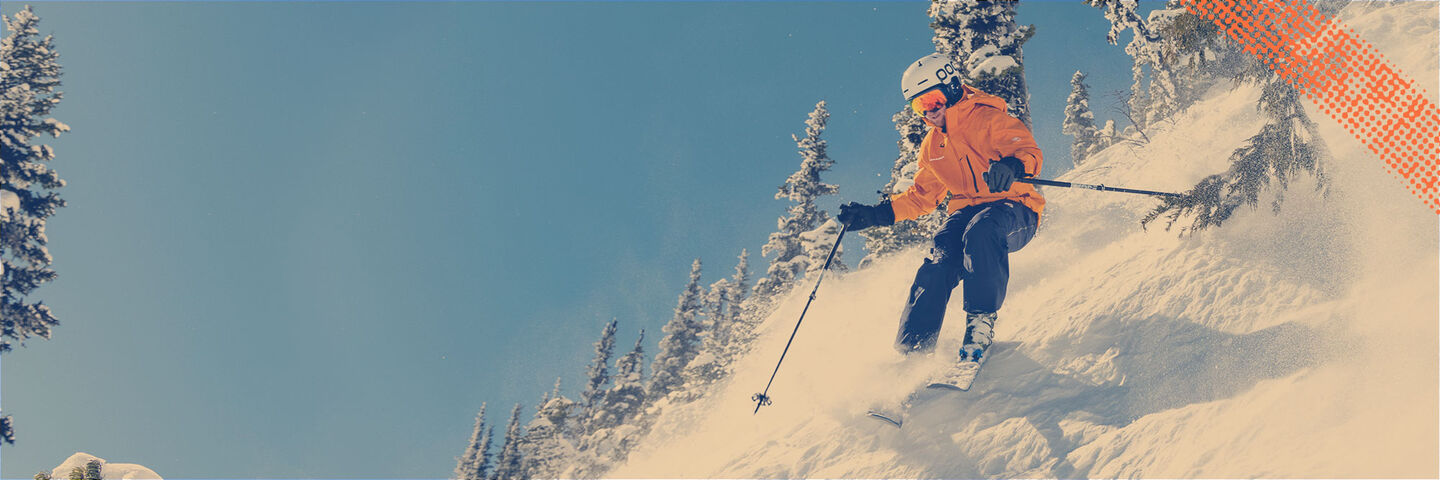 Skier carving on mountain with blue skies