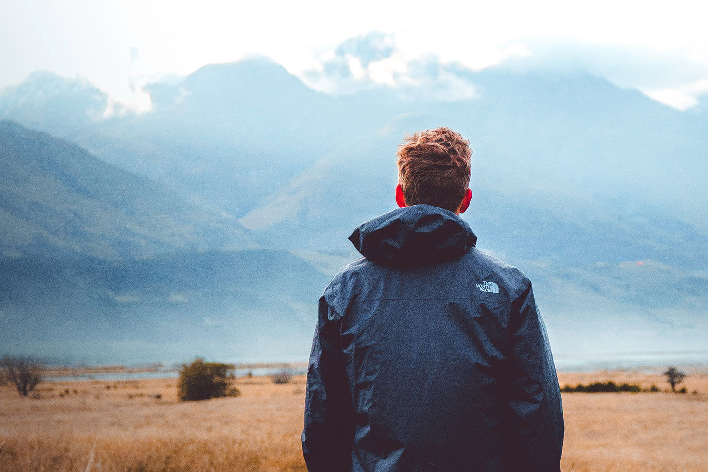 Man looking off into distance at mountains in a winter jacket