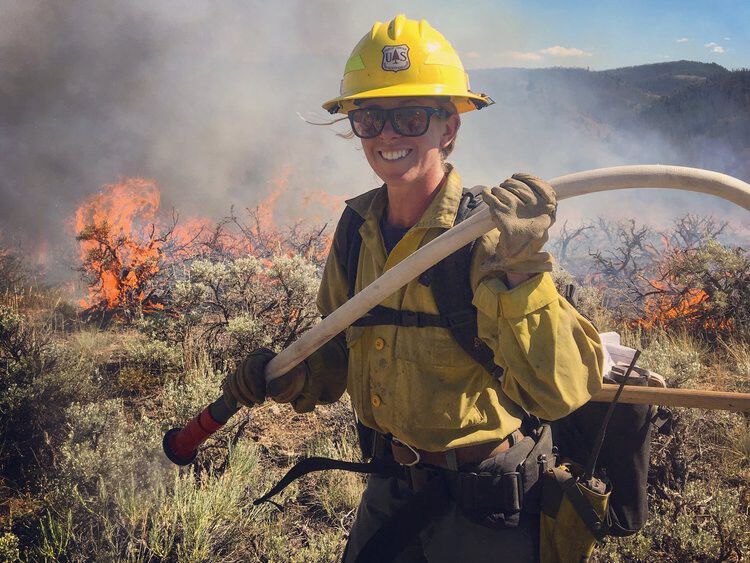 Fire Fighter woman carrying hose