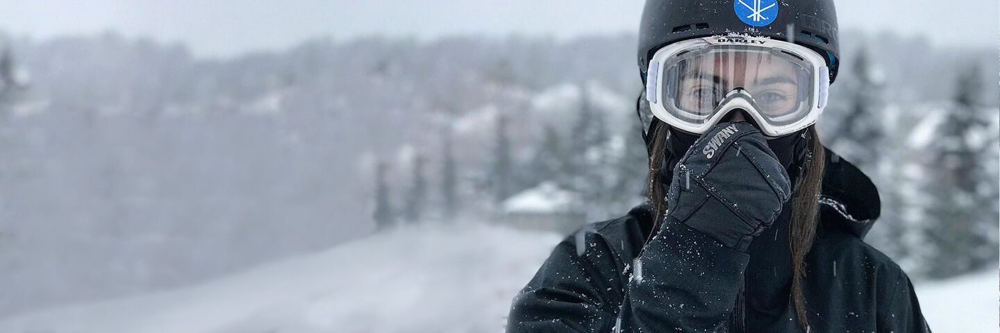 woman in ski gear wearing swany mittens on a snowy day