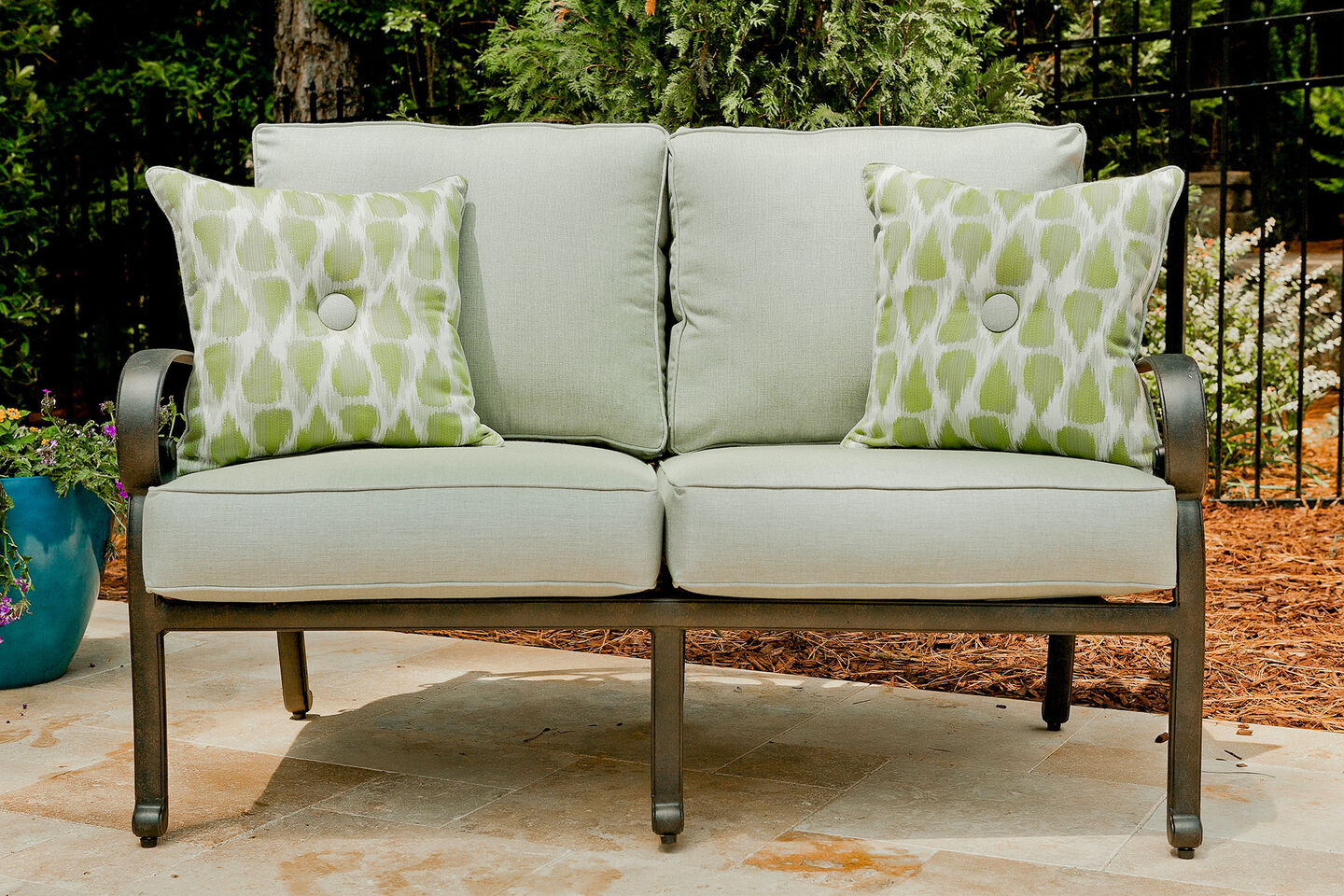 Durable gray and green outdoor cushions & pillows on a loveseat