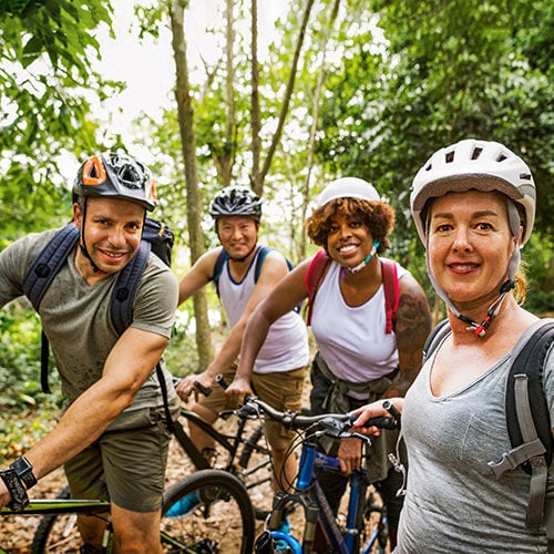 adults outside taking a selfie while enjoying a bike ride through the trees