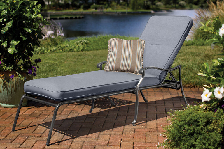 Madison by Aty chaise lounge with blue cuspricihion and striped accent pillow on brick patio