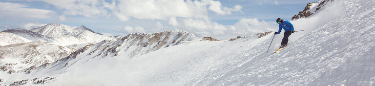 skier dropping in above tree line