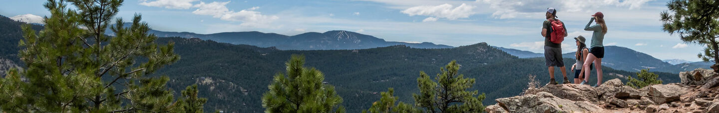 Group of hikers outside looking out at beautiful mountain view during a hike