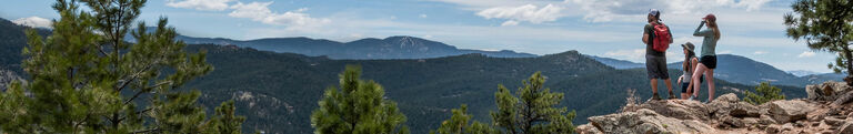 Group of hikers outside looking out at beautiful mountain view during a hike