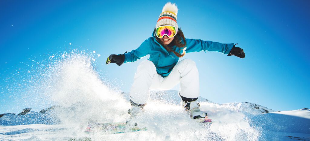 Girl jumping on a snowboard