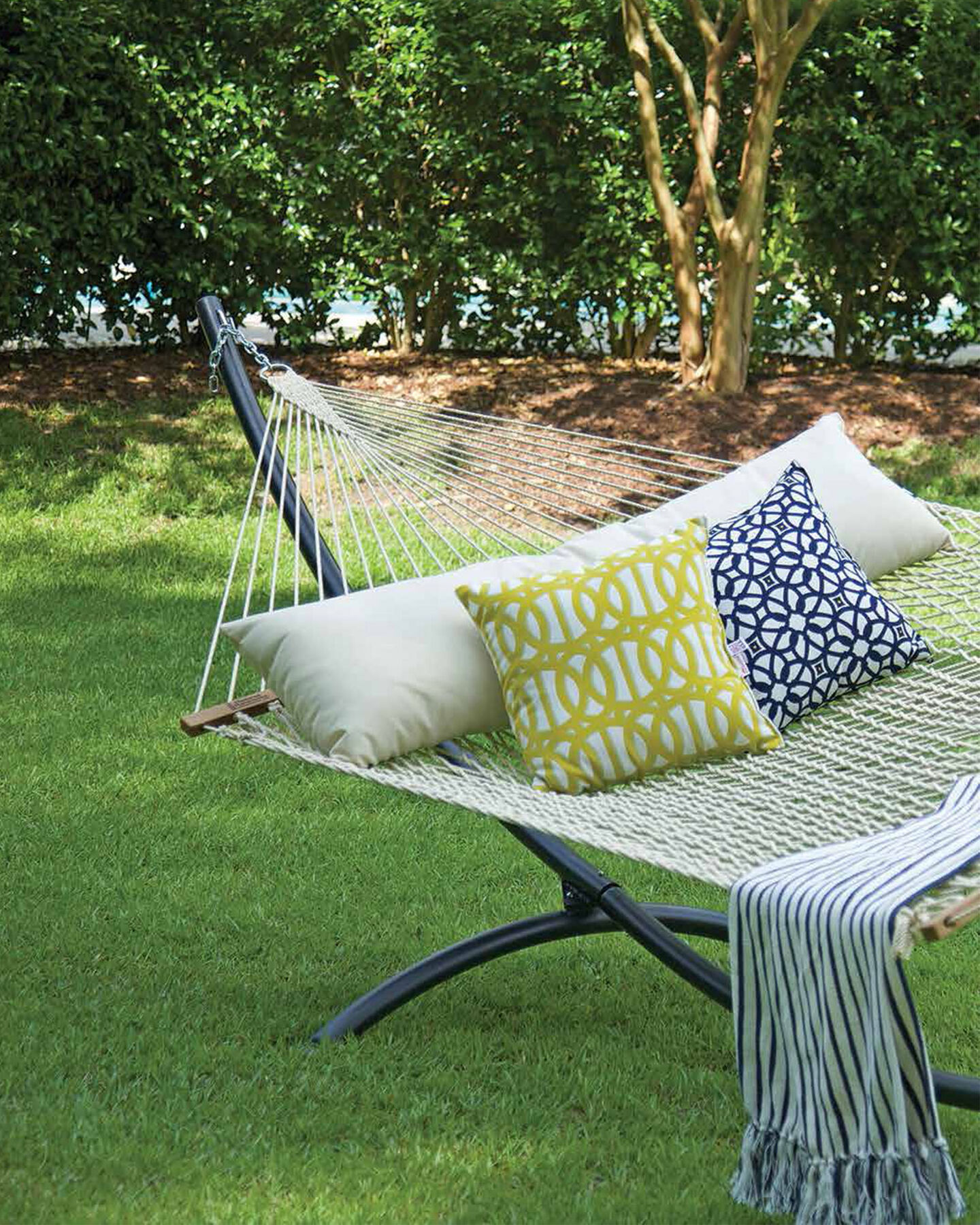 Woven hammock in the lawn under shade from surrounding trees
