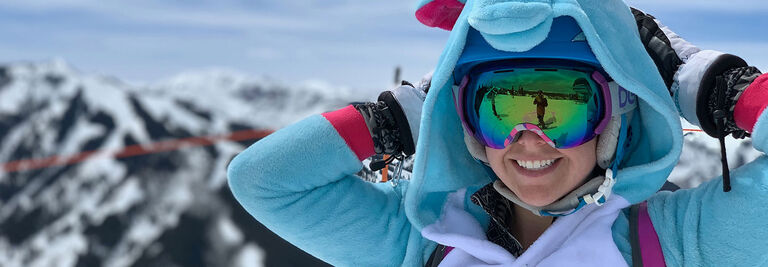 Charlotte wearing a fuzzy onesie costume with hood while skiing