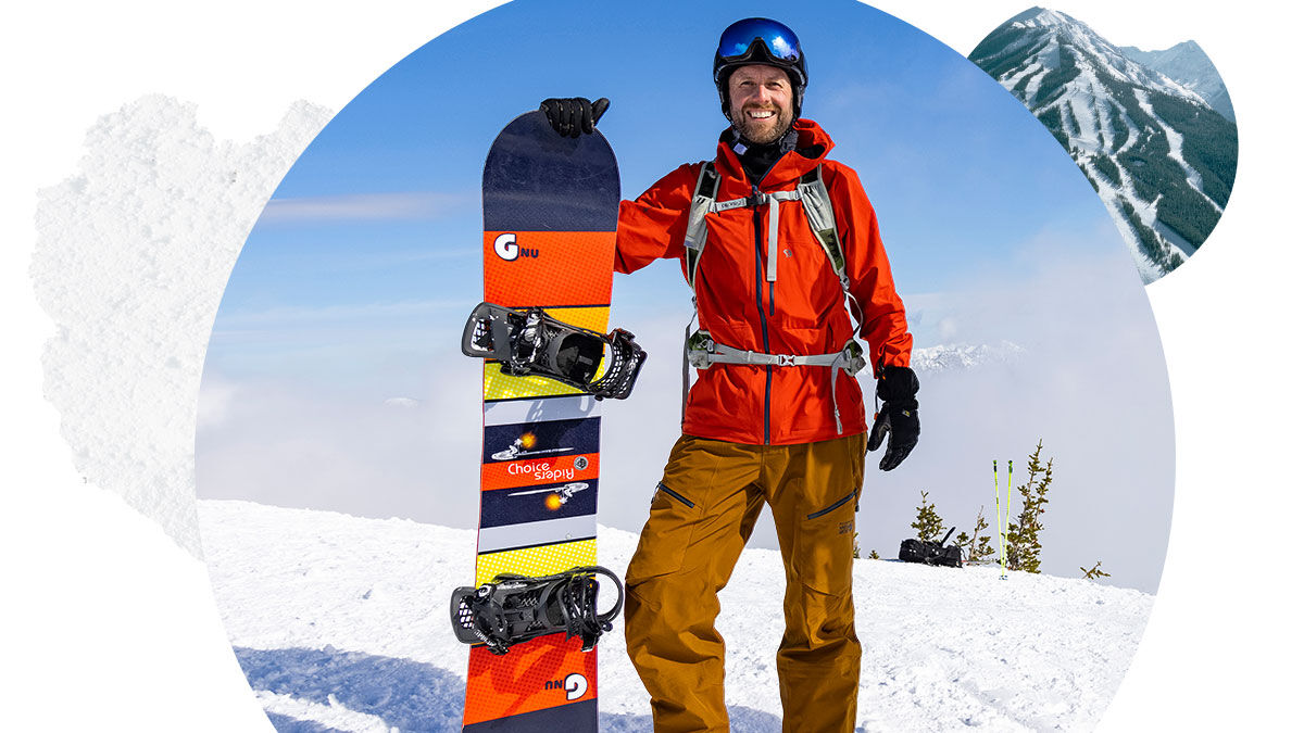 Snowboarder holding their board and smiling