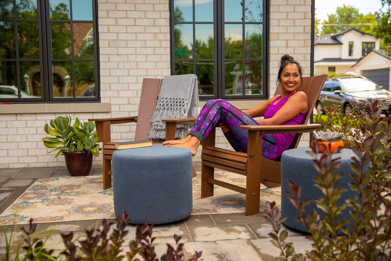 Women sitting outside in Adirondack chair with outdoor rug resting feet on pool stool