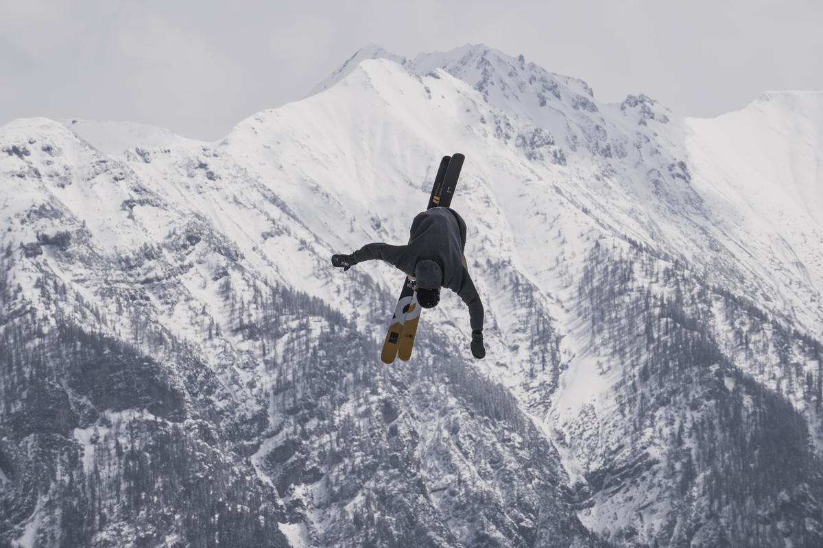man doing a flip with mountainds in the background
