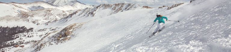 Skier in an open run above tree line