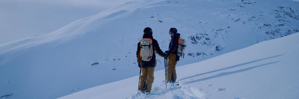 Two backcountry skiers preparing to drop in