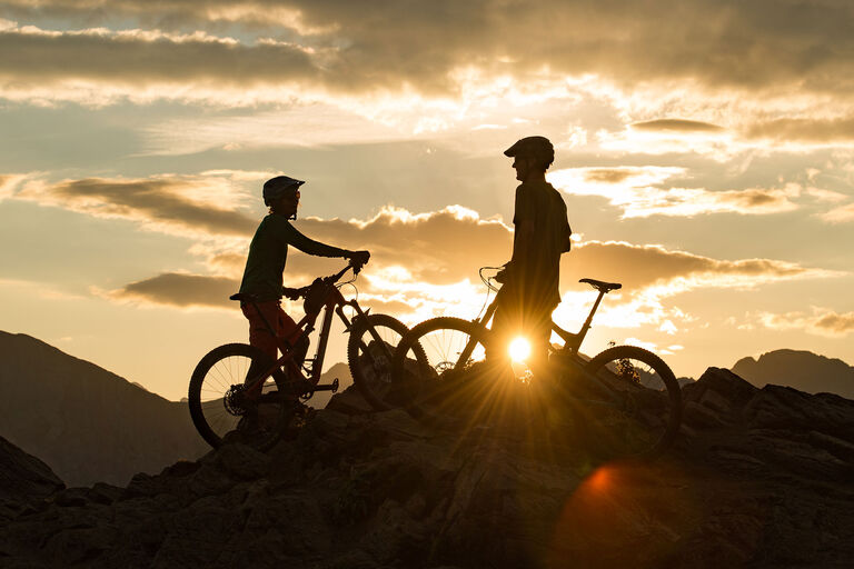 two mountain bikers enjoying the sunset after their summit