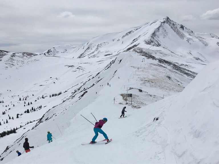 Charlotte on skis posing for a photo on a mountain ridge