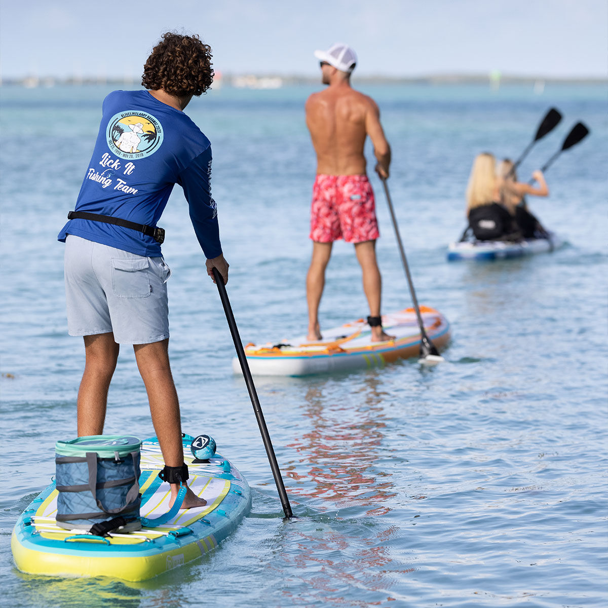 Man outside on an inflatable stand up paddleboard with a cooler