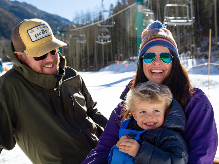 Erika with her family sitting in front of a ski lift