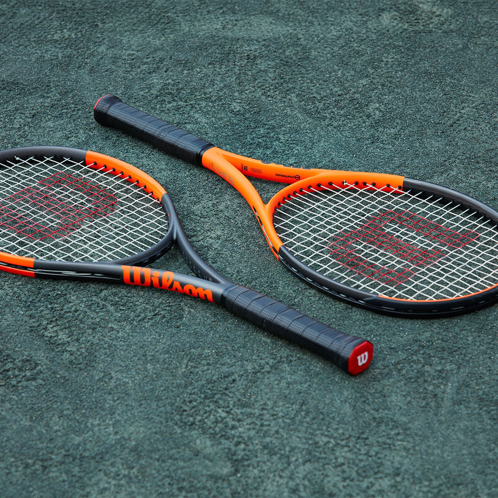 two orange and black tennis racquets on the ground
