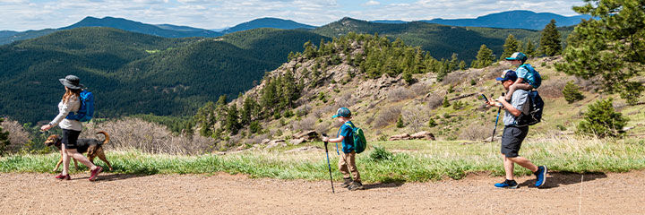 Family hiking along a trail with a mountain view in the background Family hiking along a trail with a mountain view in the background