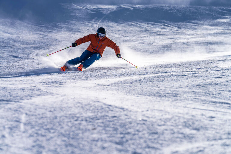 Man carving through snow on skis