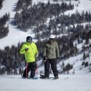 two men at the top of a ski run